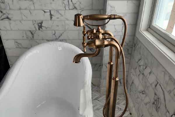 Bathroom remodeling project featuring freestanding tub with bronze faucet and marble tile walls in South Jersey home.