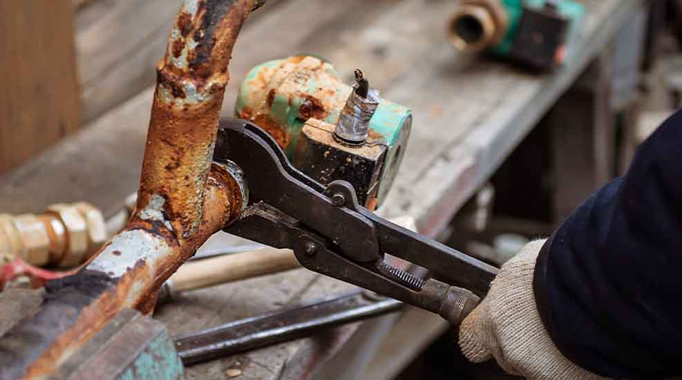 Plumber repairing corroded pipe with wrench – L.F. Fenimore Plumbing and HVAC service in South Jersey.