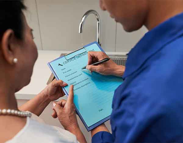 Plumbing and HVAC technician reviewing service checklist with customer for L.F. Fenimore Plumbing and HVAC in South New Jersey.